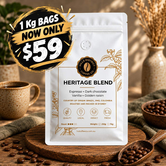 A stand-up pouch of coffee labeled 'Heritage Blend' by Halo's Distressed Coffee Co., shown on a wooden surface with coffee beans, cups, and dried flowers in the background.